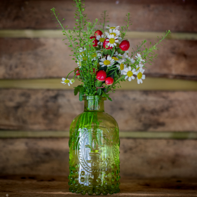 petit bouquet de marguerite et baies de roses séchées dans vase en verre vert
